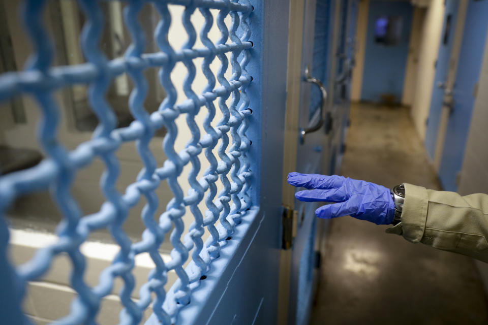 In this April 16, 2020, photo a gloved hand points to a holding cell at the hospital ward of the Twin Towers jail in Los Angeles. Across the country first responders who've fallen ill from COVID-19, recovered have begun the harrowing experience of returning to jobs that put them back on the front lines of America's fight against the novel coronavirus. (AP Photo/Chris Carlson)