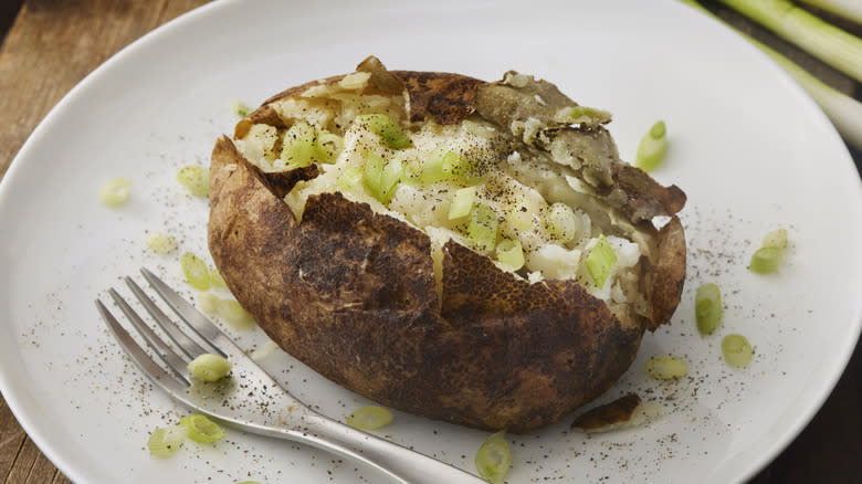 Baked potato garnished with scallions 