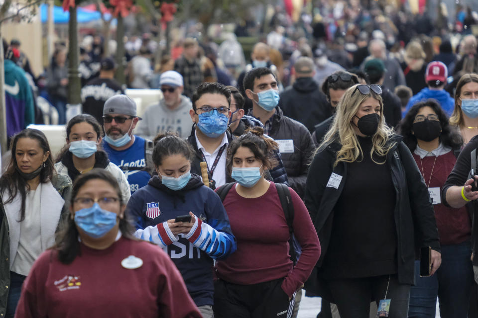 Visitors wearing face masks walk down Main Street USA at Disneyland in Anaheim, Calif.