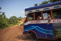 Milagros de Jesus Portocarrero holds the portrait of her mother Angelica de Jesus as she returns to her home on a bus, after a visit to her mother's burial site in a field near the San Juan cemetery, on the outskirts of Iquitos, Peru, Saturday, March 20, 2021. Almost a year ago, Angelica de Jesus and dozens of other victims were clandestinely buried in a field approved by local authorities but never told the families, who believed their loved ones were interred in the nearby San Juan cemetery. (AP Photo/Rodrigo Abd)