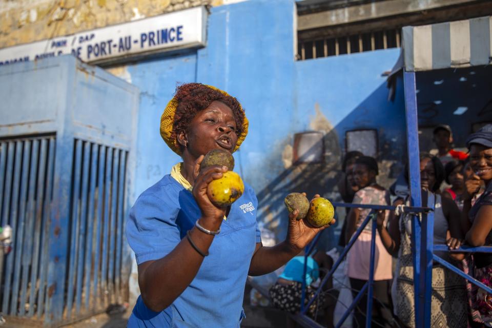 Charlene Paul Emile vende mangos frente a la Penitenciaría Nacional del Puerto Príncipe, Haití, después de llevarle comida a su hermano menor, que está preso. Foto del 25 de enero del 2021. (AP Photo/Dieu Nalio Chery)