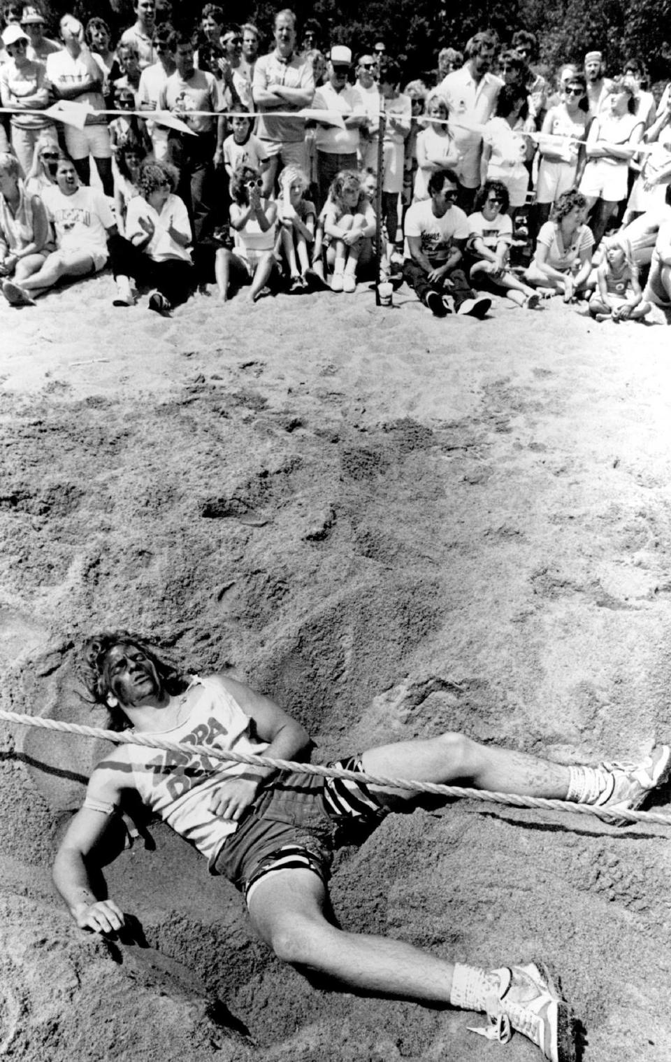 An exhausted Matt Gann rests in the sand after his team lost a round in the tug of war competition at the 1988 Wichita River Festival.