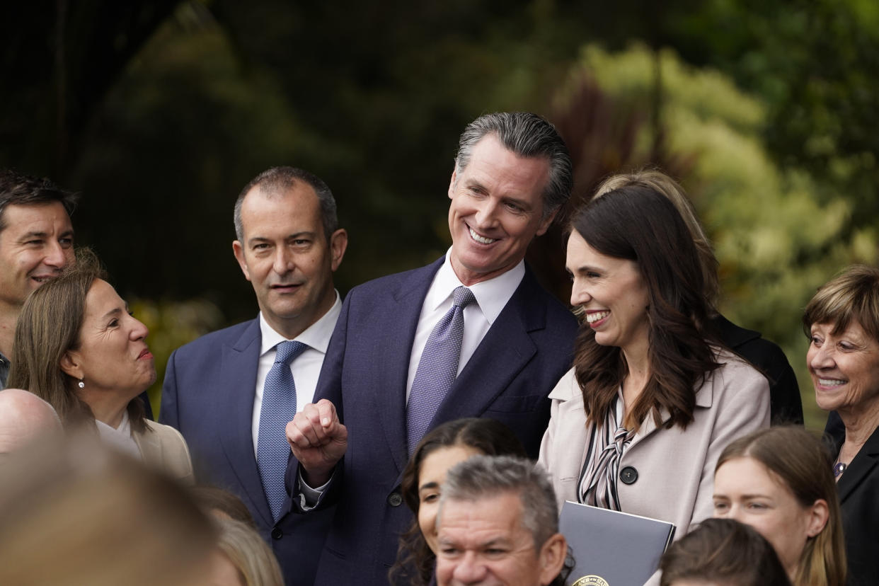 California Gov. Gavin Newsom and New Zealand Prime Minister Jacinda Ardern laugh while posing in a group photo after an event at the San Francisco Botanical Garden in San Francisco, Friday, May 27, 2022. Newsom met with Ardern in Golden Gate Park "to establish a new international partnership tackling climate change." At lower left is California Lt. Gov. Eleni Kounalakis. (AP Photo/Eric Risberg)
