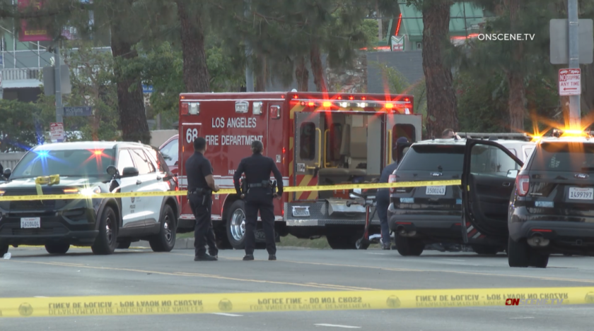 Police cruisers next to a Los Angeles Fire Department ambulance behind yellow police tape