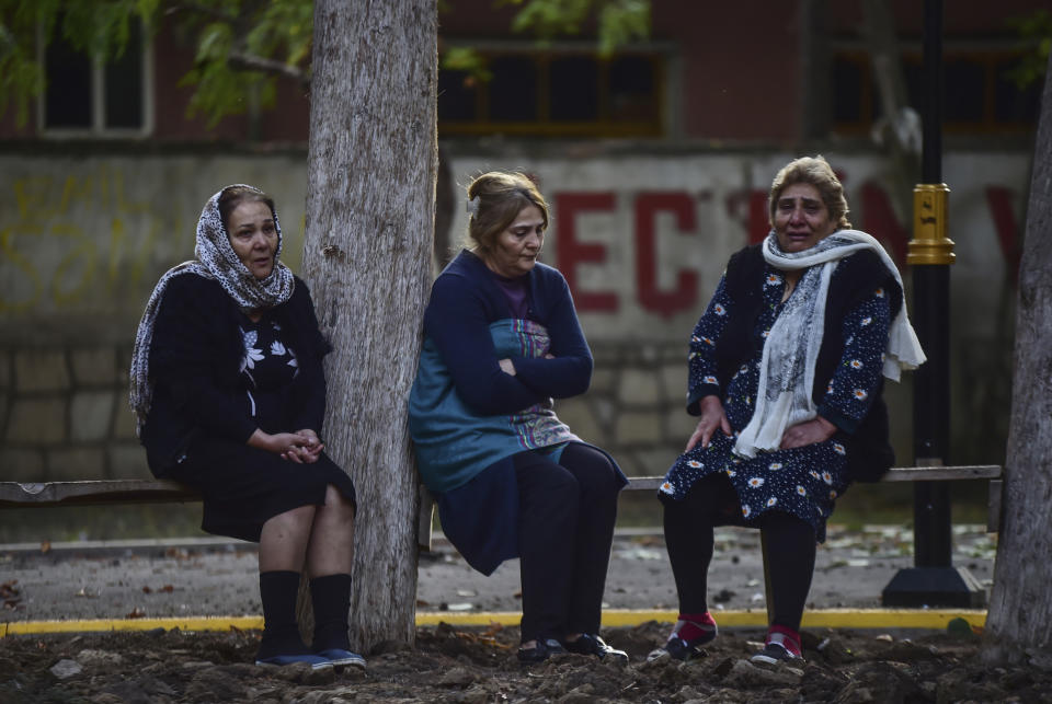 Women sit outside their damaged houses after rocket fire overnight by Armenian forces, early Sunday, Oct. 11, 2020, in a residential area in Ganja, Azerbaijan's second largest city, near the border with Armenia. Several civilians were killed and dozens were wounded. Russian President Vladimir Putin brokered a cease-fire on Friday in a series of calls with President Ilham Aliyev of Azerbaijan and Armenia's Prime Minister Nikol Pashinian. (Ismail Coskun/IHA via AP)
