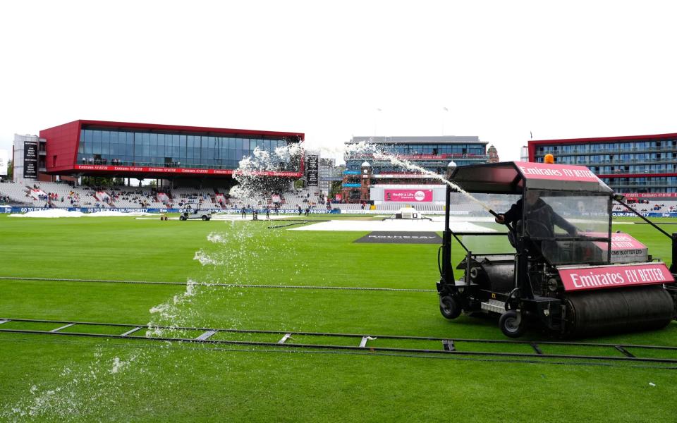 Ground staff attempt to clear the water off the field during day two of the First Rothesay Test match at the Emirates Old Trafford, Manchester