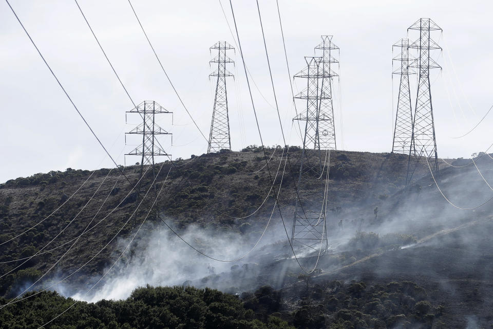 A fire crew works near power lines and electrical towers at a fire on San Bruno Mountain near Brisbane, Calif., Thursday, Oct. 10, 2019. (AP Photo/Jeff Chiu)