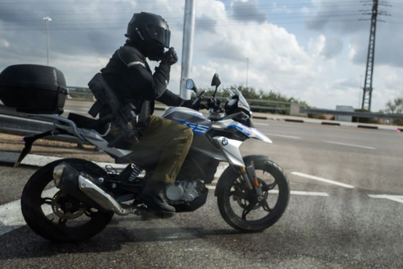 An Israeli reserve soldier armed with an assault rifle rides his motorcycle in southern Israel towards the Gaza Strip area on Thursday. Photo by Jim Hollander/UPI