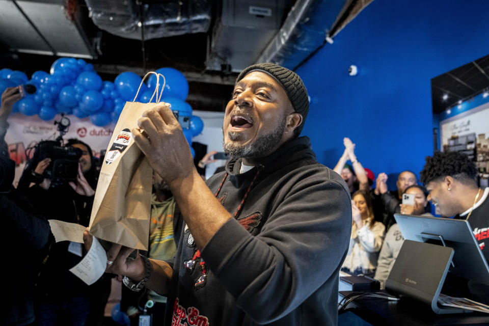 Roland Conner holds the first legal purchase of cannabis, bought from his son Darius, far right, in the "pop up" dispensary location of their business Smacked Tuesday, Jan. 24, 2023, in New York. The store is the first Conditional Adult-Use Retail Dispensary (CAURD) opening since the legalization of cannabis that is run by businesspeople who had been criminalized by cannabis prohibition. (AP Photo/John Minchillo)