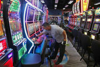 Tobias Morales disinfects gaming machines in preparation for the reopening of Lucky Star Casino after a temporary shutdown due to coronavirus concerns, Friday, May 15, 2020, in Concho, Okla. Employees are required to wear facial coverings while facial coverings are encouraged for casino guests. (AP Photo/Sue Ogrocki)