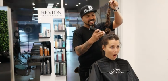 A hairdresser prepares to shave off Heather Maltman's ponytail in a salon