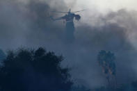 A helicopter makes a water drop on the Lilac Fire, a fast moving wild fire in Bonsall, California, U.S., December 7, 2017. REUTERS/Mike Blake