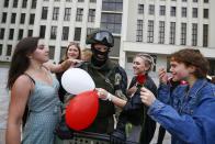 Women greet a soldier guarding the Belarusian Government building, in an exaggerated show of friendliness, in Minsk, Belarus, Friday, Aug. 14, 2020. Some thousands of people have gathered in the centre of the Belarus capital, Minsk, in a show of anger over a recent brutal police crackdown on peaceful protesters that followed a disputed presidential election. (AP Photo/Sergei Grits)