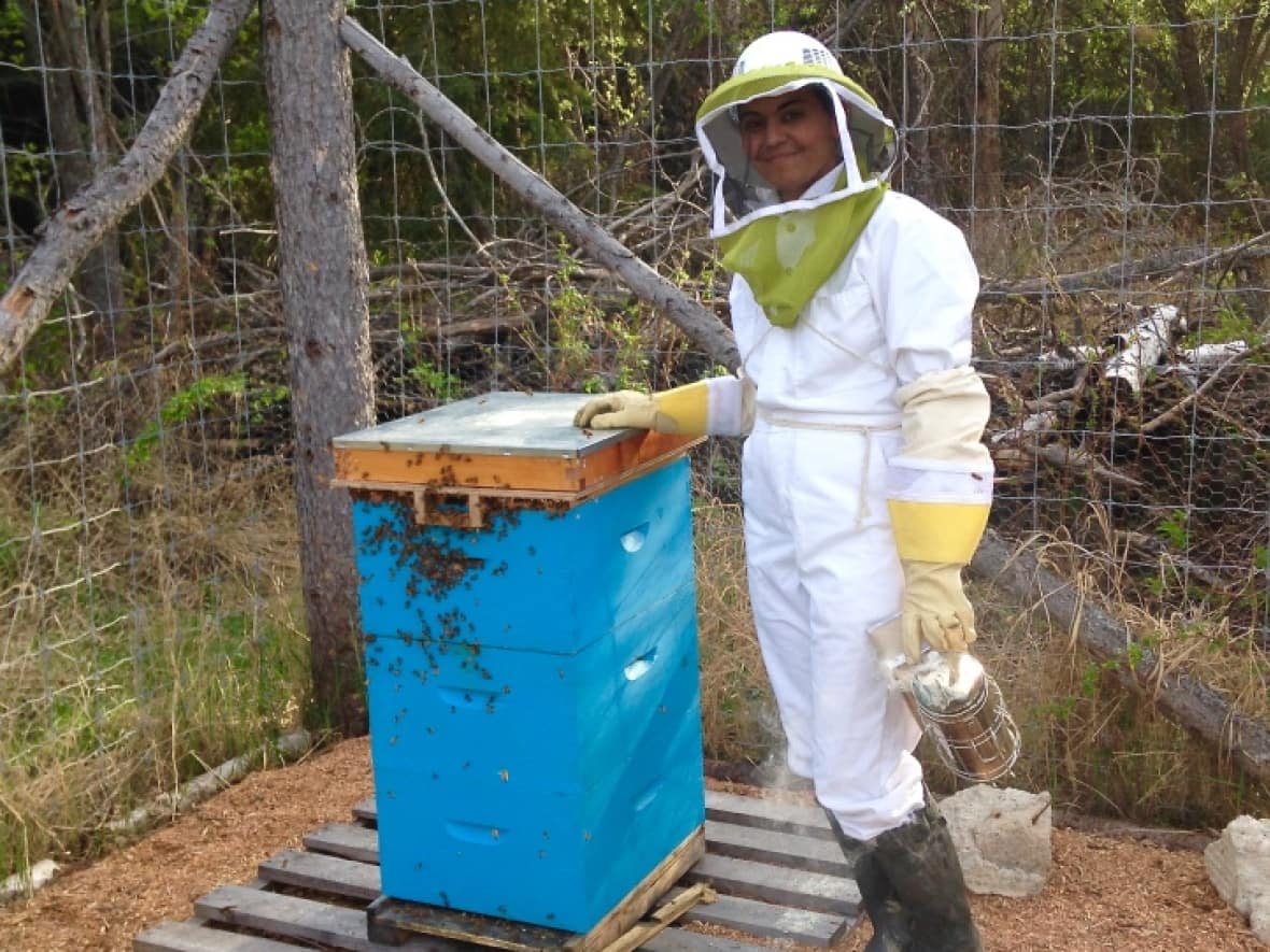 Jenna Butler at her farm in northern Alberta working with her bees. The author's book, Revery: A Year of Bees, is based on her experience as a trauma-survivor tending to bees.  (Yasmin Butler - image credit)