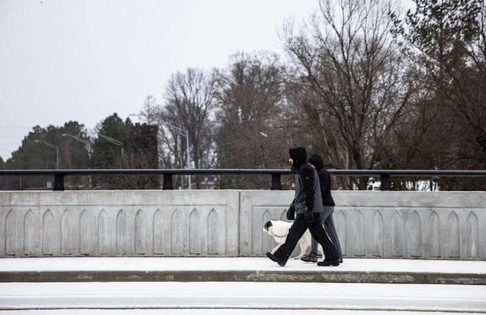 A couple walks their dog during winter weather in Charlotte, N.C., on Sunday, January 16, 2022.