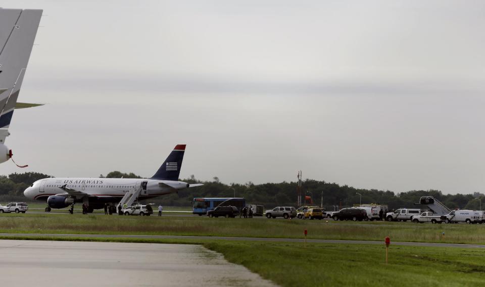 Emergency personnel look over a US Airways plane at Philadelphia International Airport, after the plane returned to the airport, Thursday, Sept. 6, 2012, in Philadelphia. Airport spokeswoman Victoria Lupica says US Airways Flight 1267 returned to the airport Thursday morning as a "precaution." Footage from WCAU-TV showed a person being escorted off the plane by law enforcement officials and police dogs on the tarmac. An FBI spokesman did not immediately comment on the situation.(AP Photo/Matt Rourke)