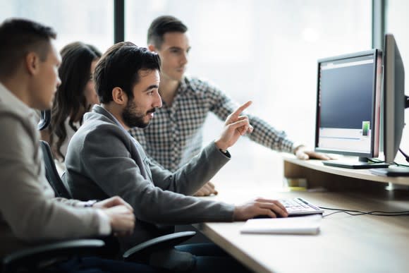 Multiple software engineers looking at two computer monitors