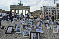 This photo provided by Syrian activist Wafaa Mustafa, shows families of Syrian detainees carrying photos of their detained the missing loved ones, as they demanding their freedom and the revealing of their fate and whereabouts during a sit-in, in Berlin Germany, on Saturday, May, 7, 2022. A newly released video taken in 2013 showed blindfolded men who were thrown into a large pit and shot dead by Syrian agents, who then set the bodies on fire. The video stirs new fears over the fate of tens of thousands who went missing during Syria's long-running conflict and serves as a grim reminder of the war's unpunished massacres, just as similar atrocities take place in Ukraine. (Wafaa Mustafa, via AP)