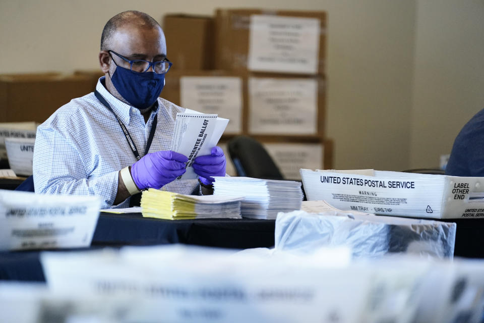 An election inspector looks at an absentee ballot as vote counting in the general election continues at State Farm Arena, Wednesday, Nov. 4, 2020, in Atlanta. (AP Photo/Brynn Anderson)