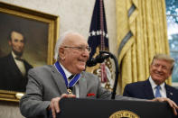 Former NBA basketball player and coach Bob Cousy, of the Boston Celtics, speaks as President Donald Trump smiles during a Presidential Medal of Freedom ceremony for Cousy, in the Oval Office of the White House, Thursday, Aug. 22, 2019, in Washington. (AP Photo/Alex Brandon)