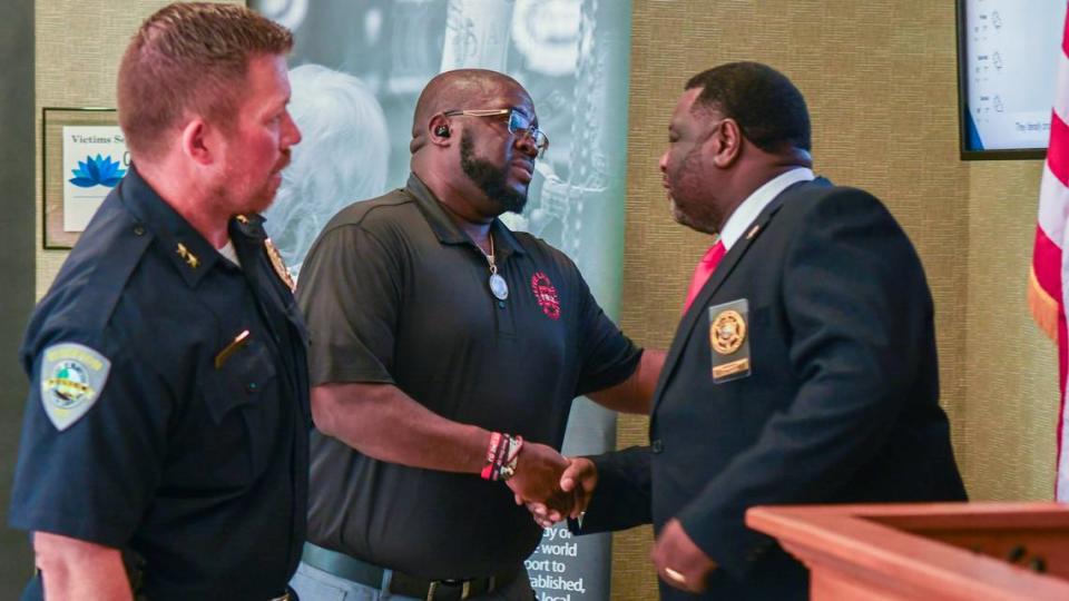 Dwon Fields, center, father of the late Bluffton teen Dwon “D.J.” Fields, shakes hands with Jasper County Sheriff Donald Hipp after 14th Circuit Solicitor Duffie Stone announced on July 6, 2023 the arrest of a man alleged to have been involved in the killing of Fields’ son in 2021. Stone says the man, 15 years old at the time of the murder, will have to be petitioned from Family Court to face a murder charge and two attempted murder charges. Drew Martin/dmartin@islandpacket.com