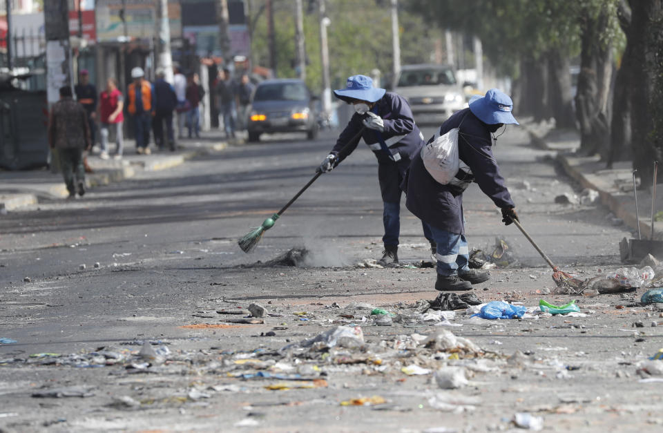 Trabajadores municipales barren escombros de una calle después de un día de disturbios en Quito, Ecuador, el viernes 4 de octubre de 2019. El presidente de Ecuador declaró el estado de excepción para enfrentar protestas callejeras y una huelga de transporte a nivel nacional por su decisión de poner fin al subsidio al combustible. (AP Foto / Dolores Ochoa)