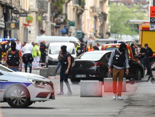 French police scour the area in Lyon after the package bomb blast that wounded more than a dozen people