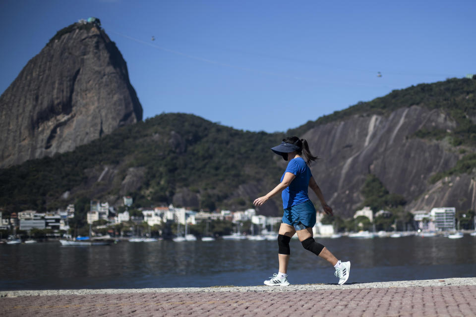 A woman walks past Sugarloaf Mountain in Rio de Janeiro, Brazil, Friday, July 23, 2021, during the COVID-19 pandemic. (AP Photo/Bruna Prado)