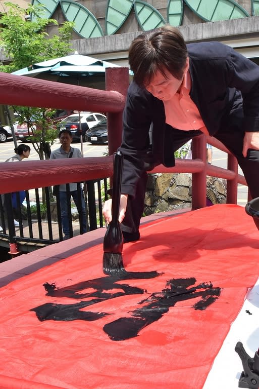 《圖說》華梵大學人文與藝術學院黃智陽院長於石碇老街拱橋揮毫。〈華梵大學提供〉