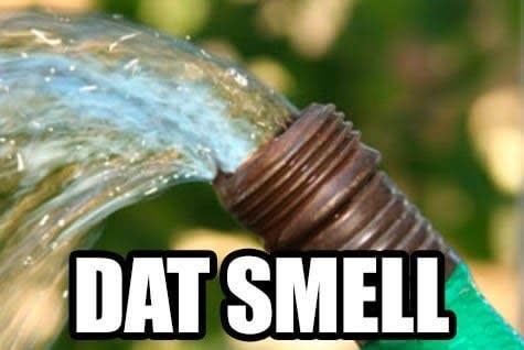Text reading "dat smell" overlaid over a photo of a hose with running water spraying upward