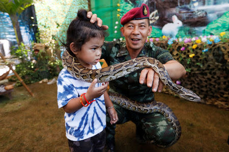 A child poses with a python during Children's Day celebration at a military facility in Bangkok, Thailand, January 13, 2018. REUTERS/Jorge Silva