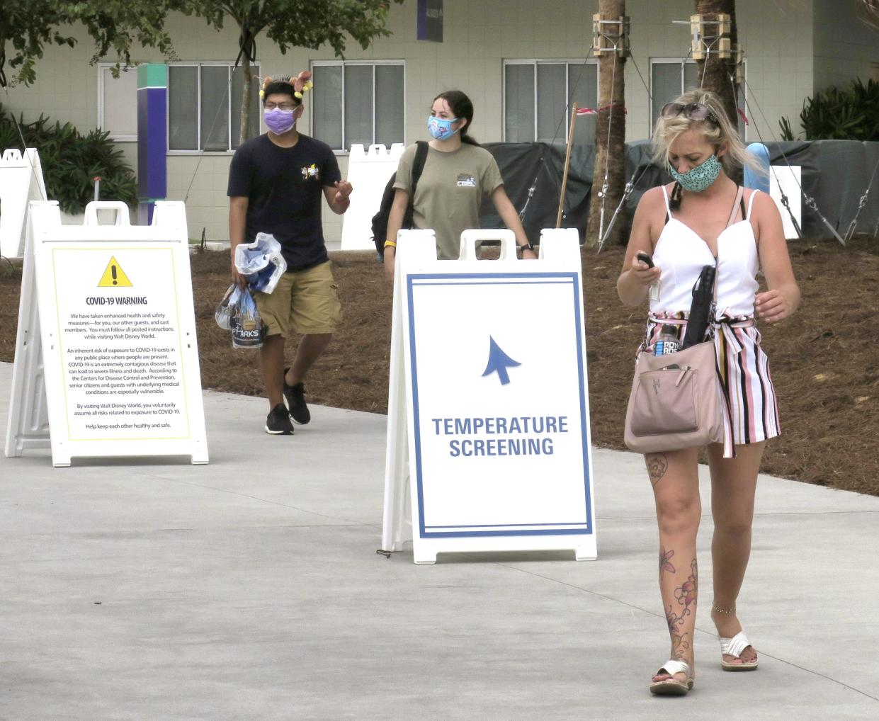 Guests wear masks as required as they arrive to attend the official reopening day of the Magic Kingdom at Walt Disney World in Lake Buena Vista, Fla., on Saturday, July 11, 2020.