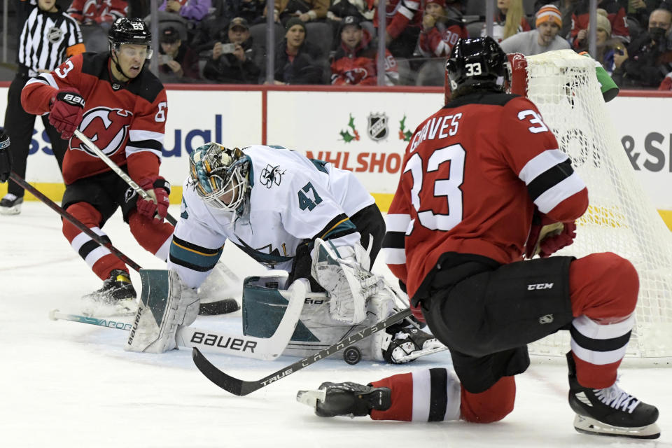 San Jose Sharks goaltender James Reimer (47) stops the puck as New Jersey Devils defenseman Ryan Graves (33) and left wing Jesper Bratt (63) look for a rebound during the first period of an NHL hockey game Tuesday, Nov. 30, 2021, in Newark, N.J. (AP Photo/Bill Kostroun)
