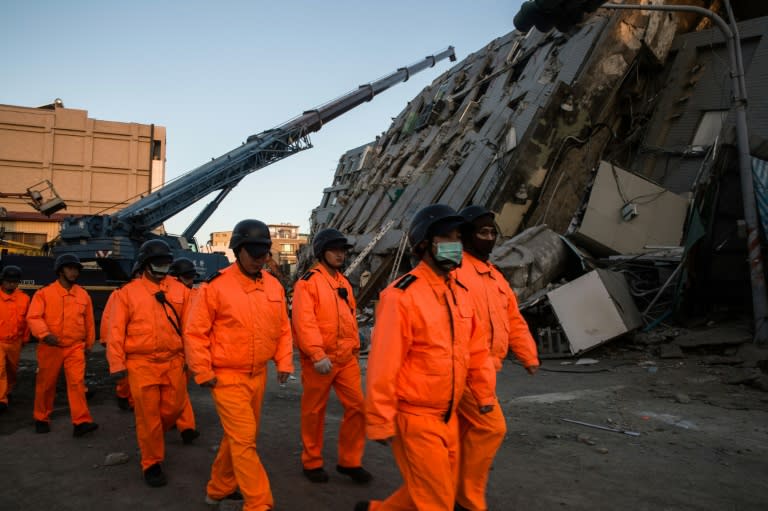 Rescue workers walk past the remains of a collapsed building in the southern Taiwanese city of Tainan on February 8, 2016