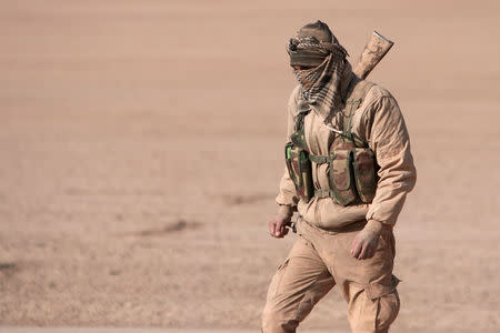 A Syrian Democratic Forces fighter walks with his weapon in northern Raqqa province, Syria. REUTERS/Rodi Said