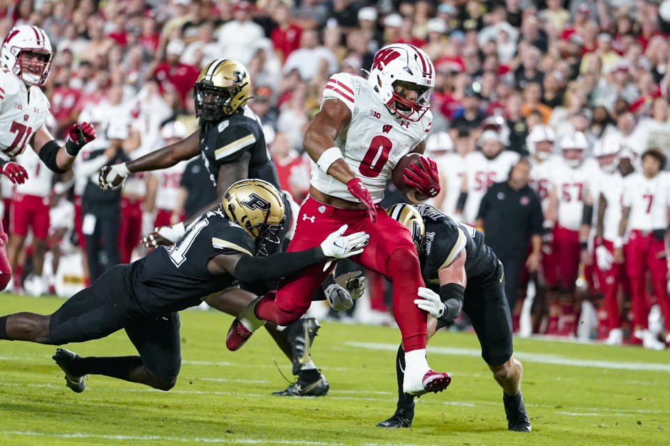 FILE - Wisconsin running back Braelon Allen (0) breaks the tackle of Purdue defensive backs Sanoussi Kane, left, and Dillon Thieneman on his way to a touchdown during the first half of an NCAA college football game in West Lafayette, Ind., Friday, Sept. 22, 2023. Allen is among the young running backs who say they love their position on the field and aren't swayed away from it by the recent hesitancy of NFL teams in handing out big contracts to running backs.(AP Photo/Michael Conroy, File)