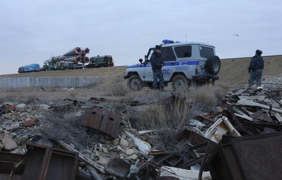 Policemen stand guard as the Soyuz TMA-12M spacecraft is transported to its launch pad at Baikonur cosmodrome