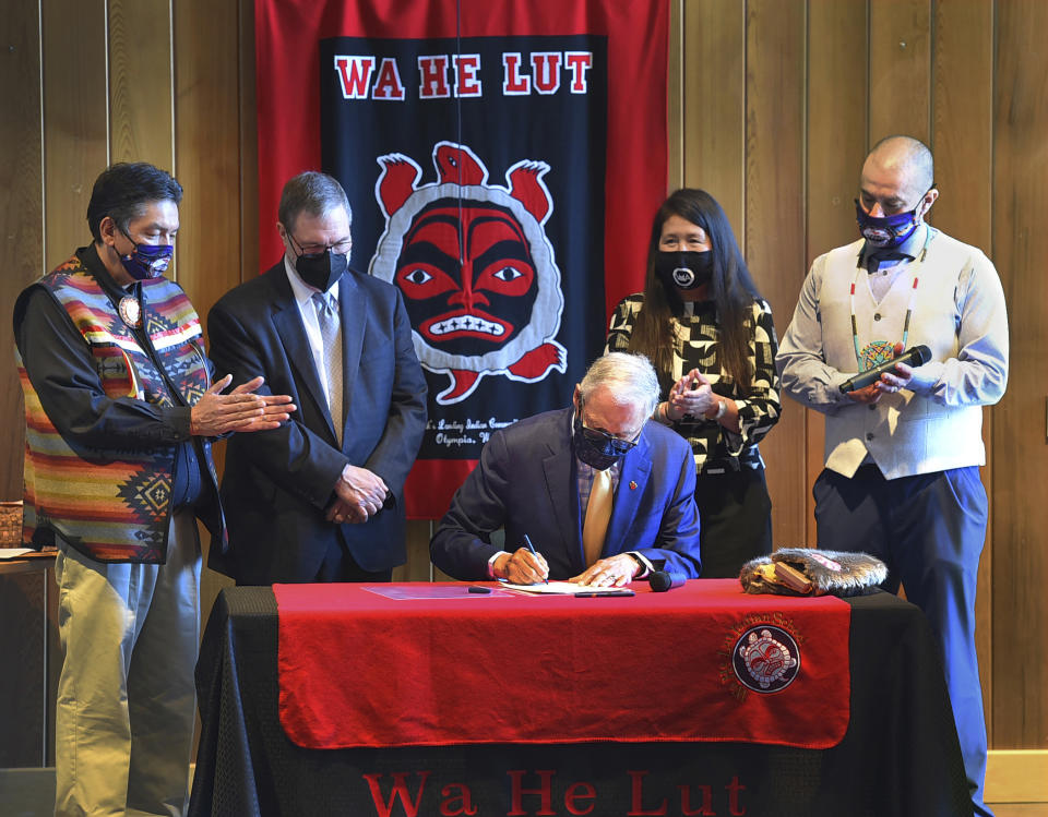 With the backdrop of the Wa He Lute Indian School near the banks of the Nisqually River in Olympia, Wash., Gov. Jay Inslee signed HB 1372 into law which paves the way for placement of a statue of Nisqually tribal leader Billy Frank Jr. to honor him at the National Statuary Hall in Washington D.C., Wednesday, April 14, 2021. Standing behind Gov Inslee, from left, Nisqually tribal chair Ken Choke, Lt. Gov. Denny Heck, Rep. Debra Lekanoff, and Willie Frank III, son of Billy Frank Jr. (Steve Bloom/The Olympian via AP)