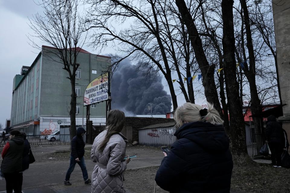 People watch smoke rising following explosions in Lviv (Nariman El-Mofty/AP)