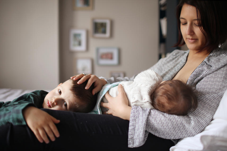 woman breastfeeding with older child next to her
