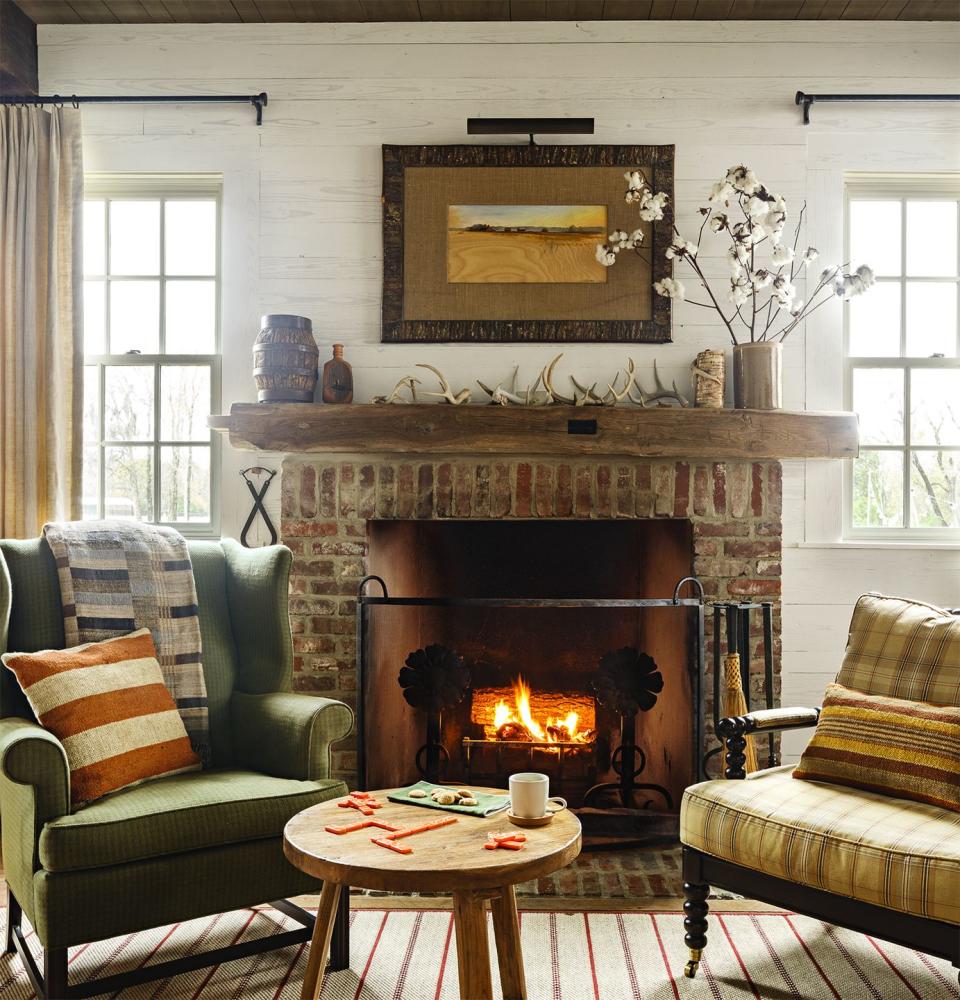 <p>This rustic vignette is pure country. Collected antlers, branches of cotton blooms, and landscape artwork in fall hues reflect a strong sense of place. The fireplace facade is made of brick pavers from an old family home.</p>