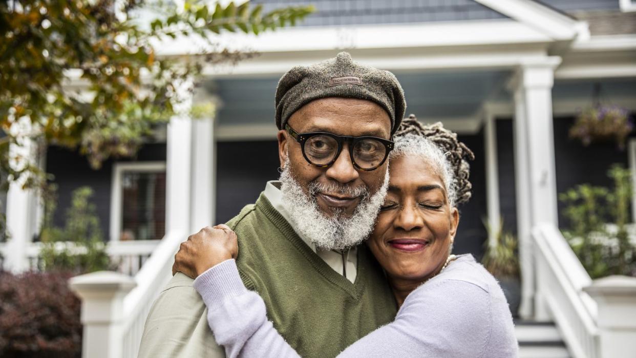 portrait of senior husband and wife in front of suburban home