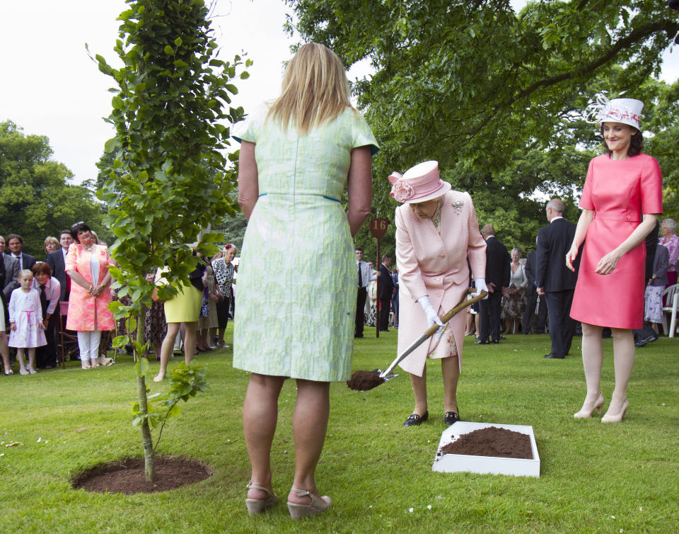 Britain's Queen Elizabeth plants a tree during a garden party at Hillsborough Castle, June 24, 2014. REUTERS/Liam McBurney/Pool (NORTHERN IRELAND - Tags: POLITICS ROYALS SOCIETY)