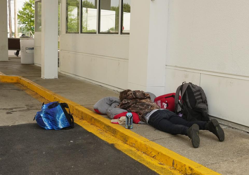 Jul 6, 2023; Columbus, Ohio, United States;  A traveler rests beside the new bus station serving Greyhound, Barons, and other bus lines at 845 N. Wilson Road on the West Side. After years of being downtown, the bus station has moved to this location, but critics are venting about crime, nuisance and traffic of the new bus depot. They also say it's just too close to their residential homes. Mandatory Credit: Doral Chenoweth-The Columbus Dispatch