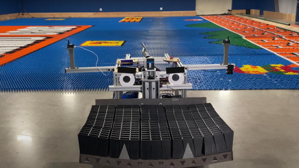 The "Dominator" Domino-laying machine in front of a field of 100,000