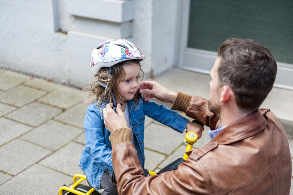 dad fastening his daughter's helmet