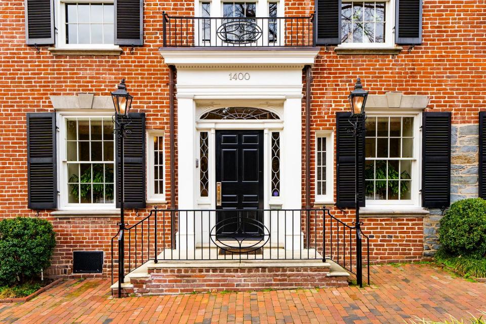 The house's charming exterior is red brick with black and white accents.