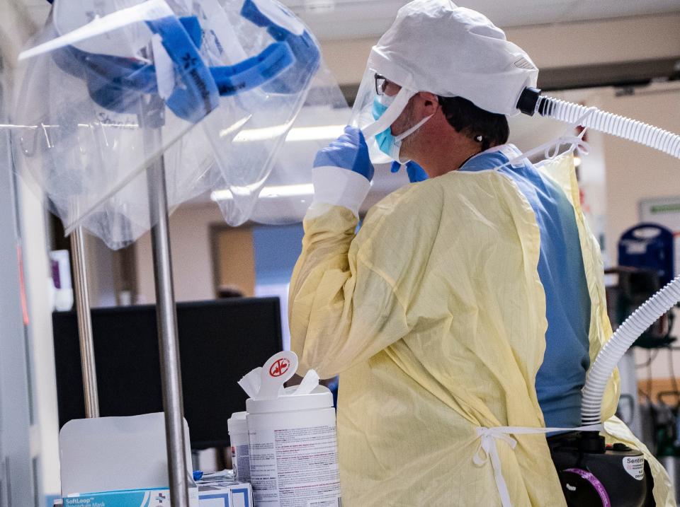 A nurse at the University of Vermont Medical Center Pediatric Intensive Care Unit (ICU) puts on PPE before entering the room of a COVID-19 positive child receiving care on Thursday, Dec. 2, 2021. For months, more and more patients with acute health conditions have landed in the ICU and a second COVID-19 surge is stretching capacity. Where a typical acute patient might spend a week or less in the ICU, COVID-19 patients can take up a bed for a month or more. 