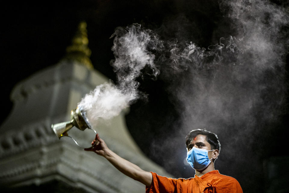 A Nepalese Hindu priest wearing face mask as a precaution against the coronavirus performs evening rituals at Pashupatinath Hindu temple in Kathmandu, Nepal, Monday, April 19, 2021. (AP Photo/Niranjan Shrestha)