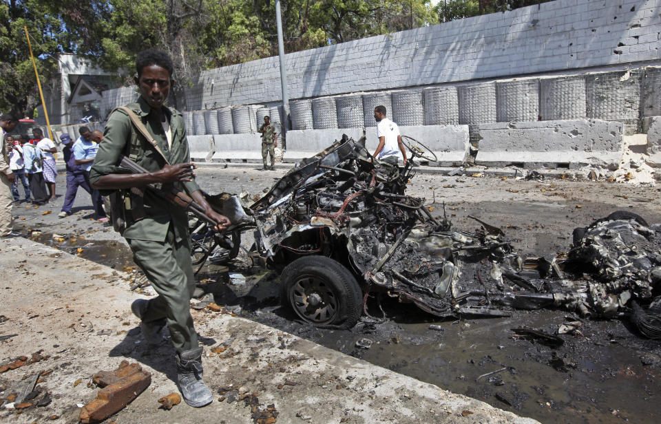 Somali soldiers walk near the wreckage of a car bomb attack in Mogadishu, Somalia Friday, March 24, 2017. A police official says the car bomb exploded near a restaurant and hotel in Somalia's capital killing at least one person and wounding others. (AP Photo/Farah Abdi Warsameh)